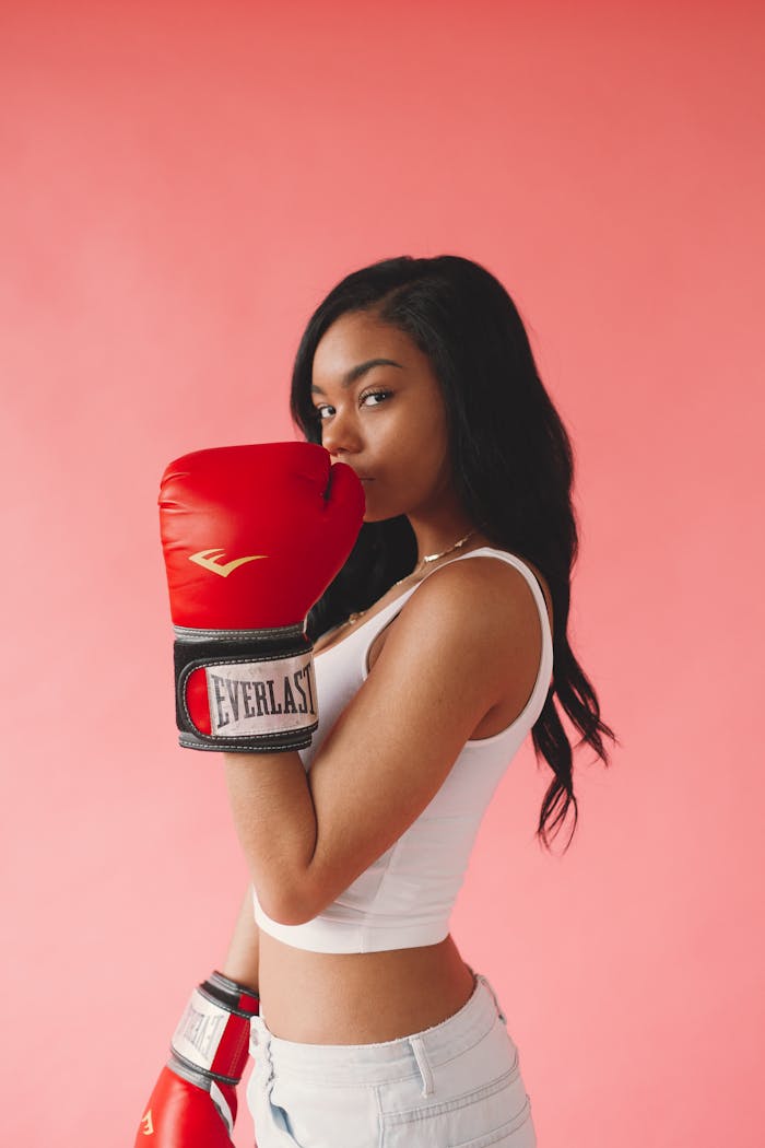 menu-03 Stylish woman posing with red boxing gloves on a pink background, exuding confidence and fitness.